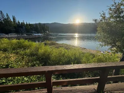 a bench sitting next to a lake with the sun setting at Wishon Lake Front, Price Reduced, 3day Min in Bass Lake