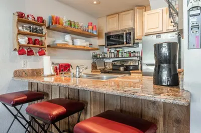 a kitchen with a counter with stools and a refrigerator at Canyon Slopeside Retreat in Mammoth Lakes