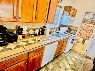 a kitchen with wooden cabinets and a white stove top oven at Lower Unit-Yosemite Woods-Inside Yosemite in Yosemite West