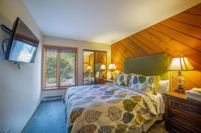 a bedroom with a large bed with a wooden wall at Plush Mammoth Condo w Balcony Views in Mammoth Lakes