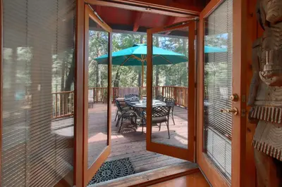 a screened porch with a table and an umbrella at Black Oak Lodge at The Redwoods in Wawona