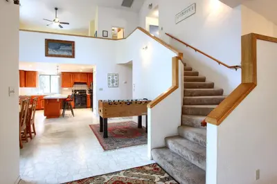 a living room with stairs and a pool table at Cabin Among the Firs in Wawona