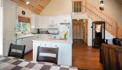 a kitchen with white cabinets and a table with chairs at Margaret's at The Redwoods in Wawona
