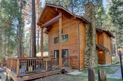 a cabin in the woods with a wrap around deck at Cabin Twelve in Wawona