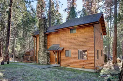 a log cabin in the woods with a yard at Cabin Twelve in Wawona