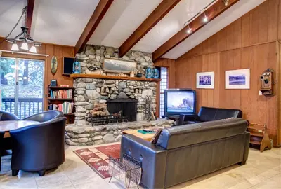 a living room with a couch and a stone fireplace at Star Gazers in Wawona