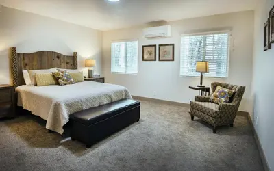 a bedroom with a bed and a chair and windows at Hilltop Haven in Wawona