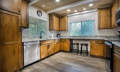 a kitchen with wooden cabinets and a sink and stools at Hilltop Haven in Wawona