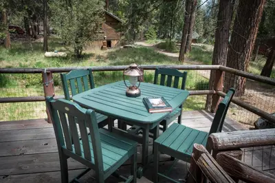 a green table with chairs and a lamp on a deck at Chipmunk Hollow in Wawona