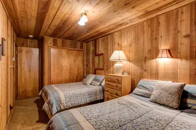 two beds in a room with wooden walls at Tyler's Timber Lodge in Wawona
