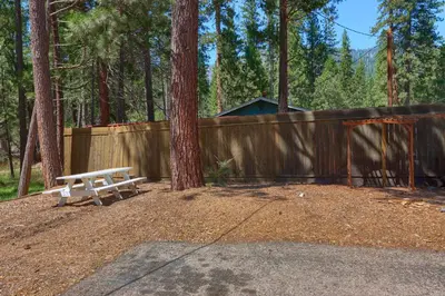 a picnic bench sitting in front of a fence at New Beginnings at The Redwoods Cabin in Wawona