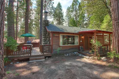 a log cabin in the woods with a deck at Le Fawn in Wawona
