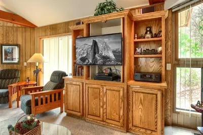 a living room with a large entertainment center with a flat screen tv at Pohono Pines in Wawona
