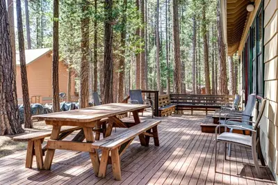 a picnic table and chairs on a deck with trees at Wawona Retreat in Wawona