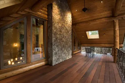 a large porch with a stone wall and wooden flooring at Rustic Retreat in Wawona