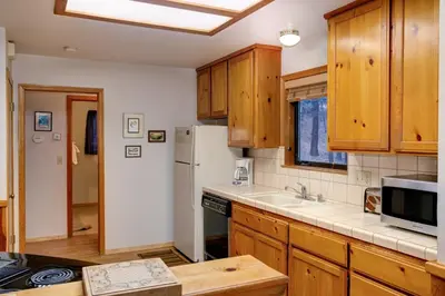 a kitchen with wooden cabinets and a refrigerator at Cecil's Cabin in Wawona