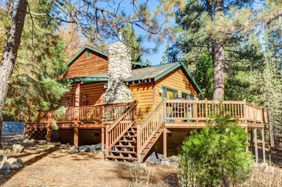 a log cabin in the woods with a large deck at River Refuge in Wawona