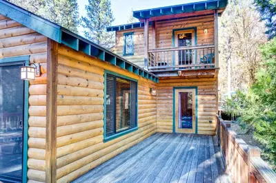 a log cabin with a deck and a balcony at River Refuge in Wawona