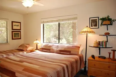 a bedroom with a bed and a window and two lamps at Big Cedar in Wawona