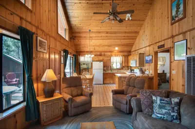 a living room with a couch and chairs and a kitchen at Wawona Cabin in Wawona
