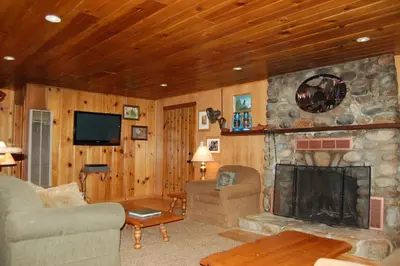 a living room with a stone fireplace and a tv at Deer Den in Wawona