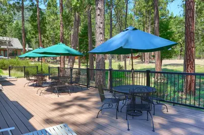 a deck with tables and chairs and umbrellas at The Terry Cabin in Wawona