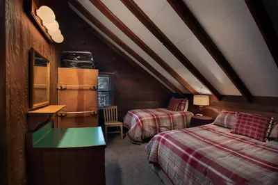 a attic bedroom with two beds and a table at Grandma's Cabin in Wawona
