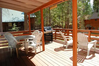 a deck with a table and chairs and a television at Cubby's Den in Wawona
