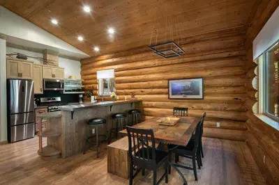 a kitchen with wooden walls and a table with chairs at The Mini Cabin in Wawona