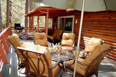 a deck with a table and chairs on a cabin at River Song in Wawona