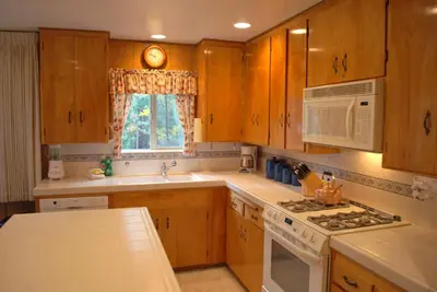 a kitchen with wooden cabinets and a sink and a microwave at River Song in Wawona