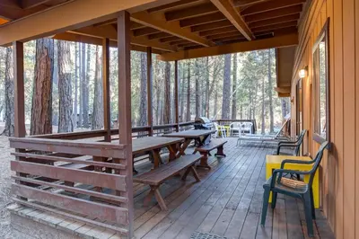 a porch of a cabin with wooden tables and chairs at Cutter's Edge in Wawona