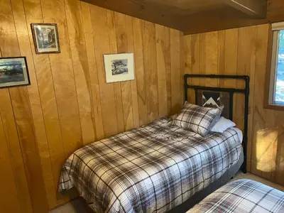 a bedroom with two beds in a wooden wall at Cutter's Edge in Wawona
