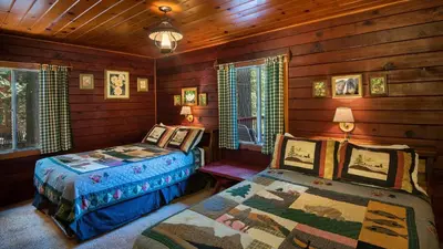 a bedroom with two beds in a log cabin at Lockwood Lodge in Wawona