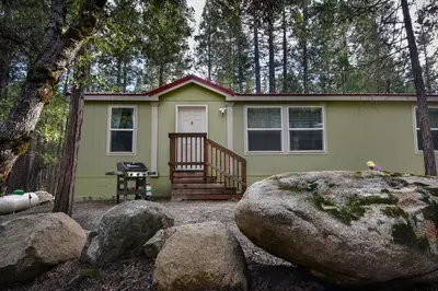 a green tiny house in the woods with rocks at Suter's Forte in Wawona