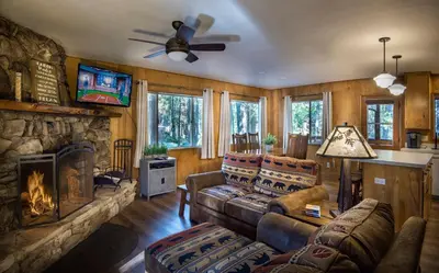 a living room with a couch and a fireplace at Pine Creek Cabin in Wawona