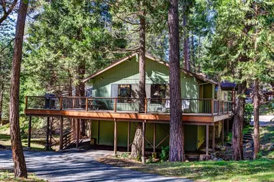 a house in the trees with a wrap around deck at Coyle's Cabin in Wawona