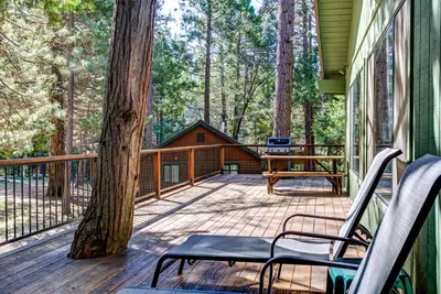 a deck with two chairs and a picnic table on it at Coyle's Cabin in Wawona