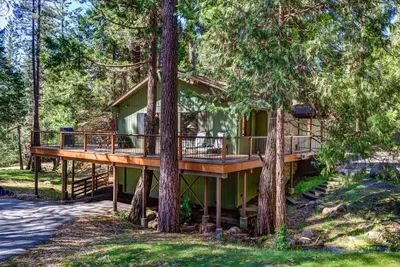 a tree house in the woods with a wrap around deck at Coyle's Cabin in Wawona