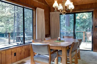 a dining room with a table and chairs and large windows at Coyle's Cabin in Wawona