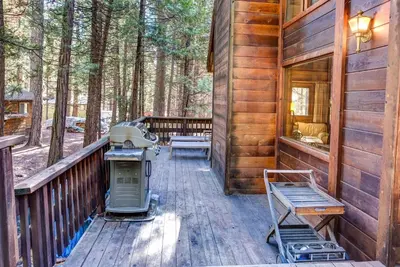 a porch of a wooden cabin with a grill on it at Cedar Chalet in Wawona