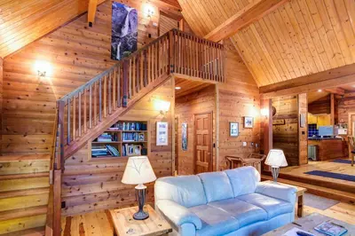 a living room with a blue couch and a staircase at Cedar Chalet in Wawona