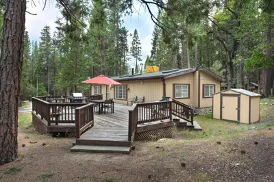 a cabin in the woods with a wooden deck at Rosenberg's Creekside Cabin in Wawona