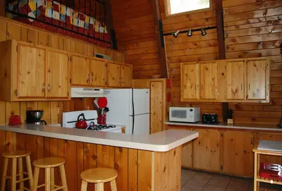 a kitchen with wooden cabinets and a white refrigerator at Manzanita Lodge in Wawona