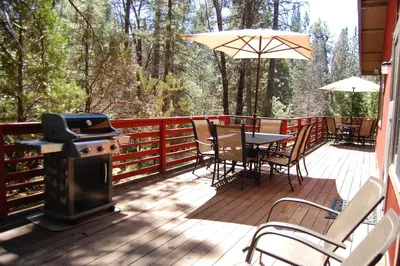 a deck with a grill and a table and chairs at Manzanita Lodge in Wawona