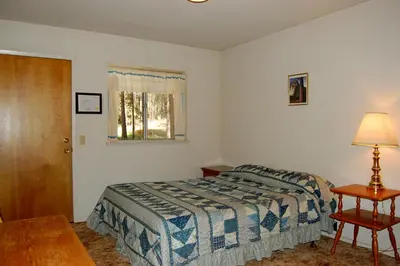 a bedroom with a bed and a table and a window at Altitude Adjustment in Wawona