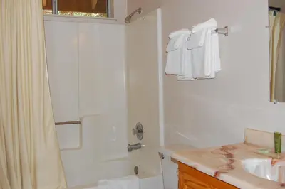 a white bathroom with a shower and a sink at Altitude Adjustment in Wawona