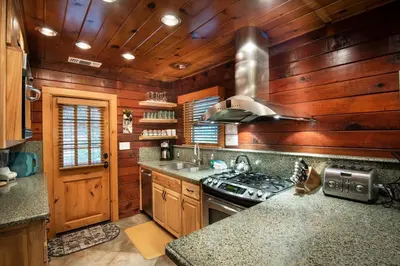 a kitchen with wooden walls and a stove top oven at Sugar Pine Suite in Wawona