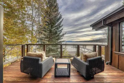 a porch with two chairs and a table on a deck at Aqua Vista Lakefront Estate by Tahoe Getaways - 6 BR in Carnelian Bay w Buoy, Pier & Game Room in Carnelian Bay