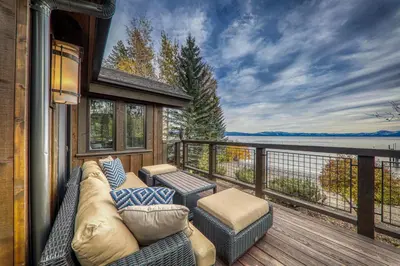 a balcony with a couch and chairs on a deck at Aqua Vista Lakefront Estate by Tahoe Getaways - 6 BR in Carnelian Bay w Buoy, Pier & Game Room in Carnelian Bay